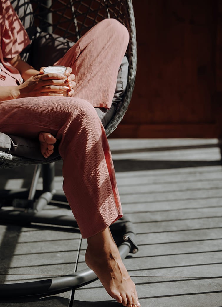 Eine Person sitzt mit einem Getr&auml;nk in der Hand in einem H&auml;ngesessel
