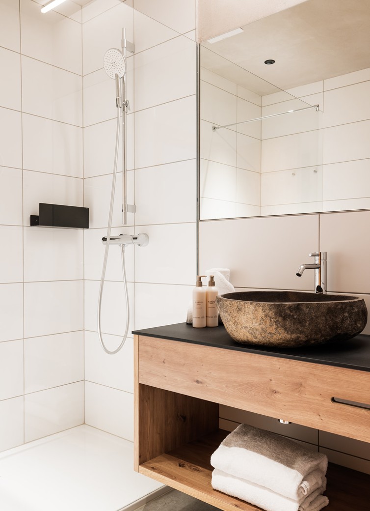 Modernes Badezimmer mit Holzwaschtisch, Steinbecken und Regendusche