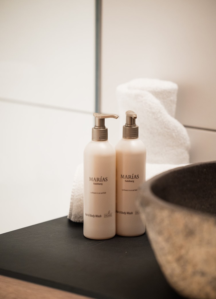 Zwei Flaschen Haar- und Körperwaschmittel neben gerollten Handtüchern