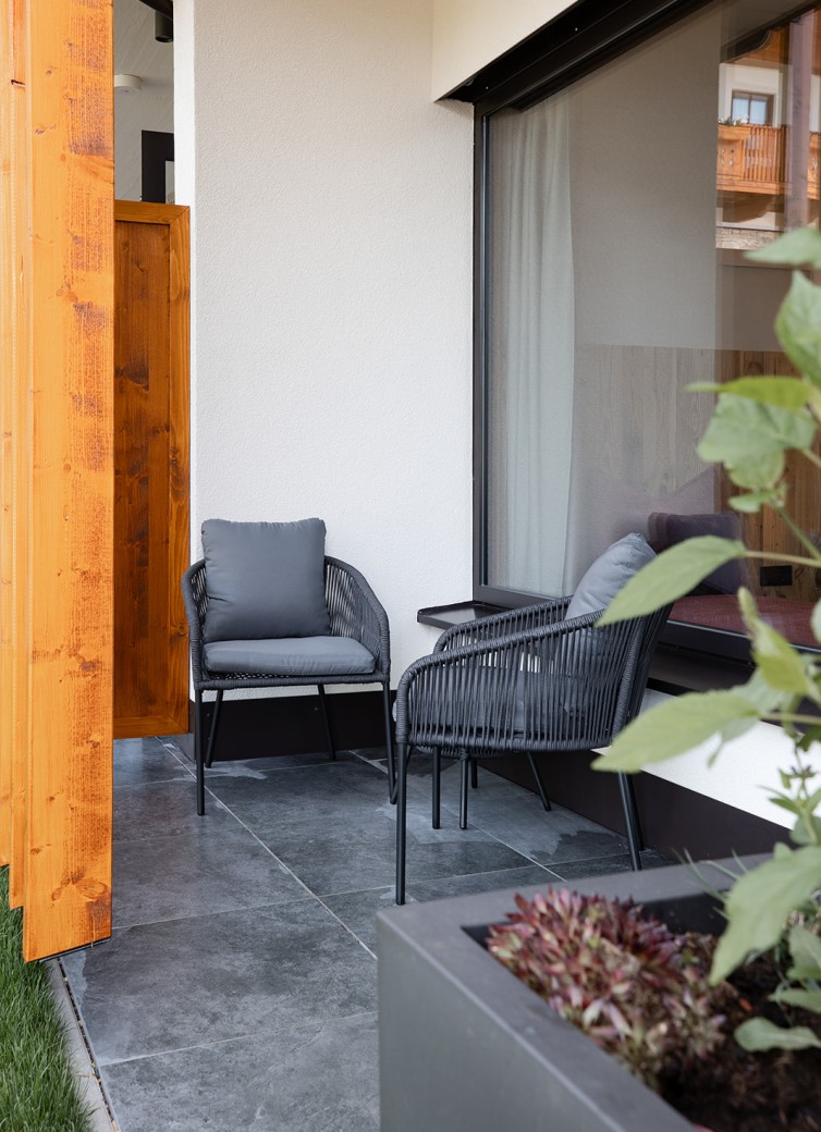 Zwei graue Sessel auf kleiner Terrasse mit Steinboden und Pflanzkübel