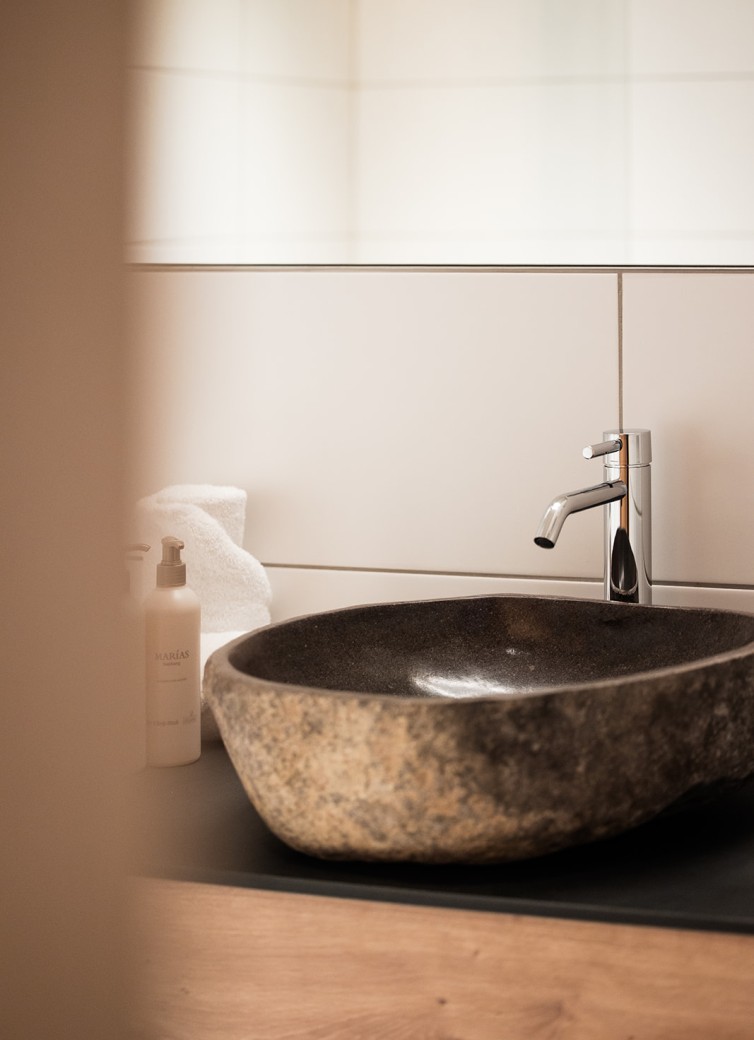 Steinbecken im modernen Badezimmer mit Wasserhahn und Handtuch im Hintergrund