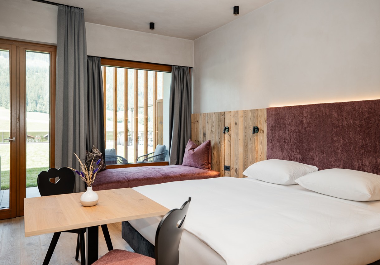 Helles Hotelzimmer mit Doppelbett, Holzmöbeln und großem Fenster mit Aussicht