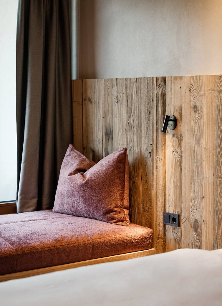 Gemütliche Sitzecke mit Holzwänden und rotem Kissen