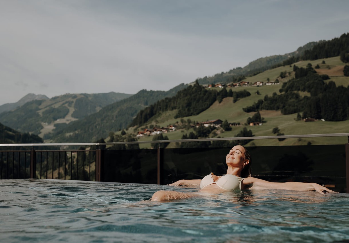 Frau entspannt im Pool mit Blick auf Großarler Berge