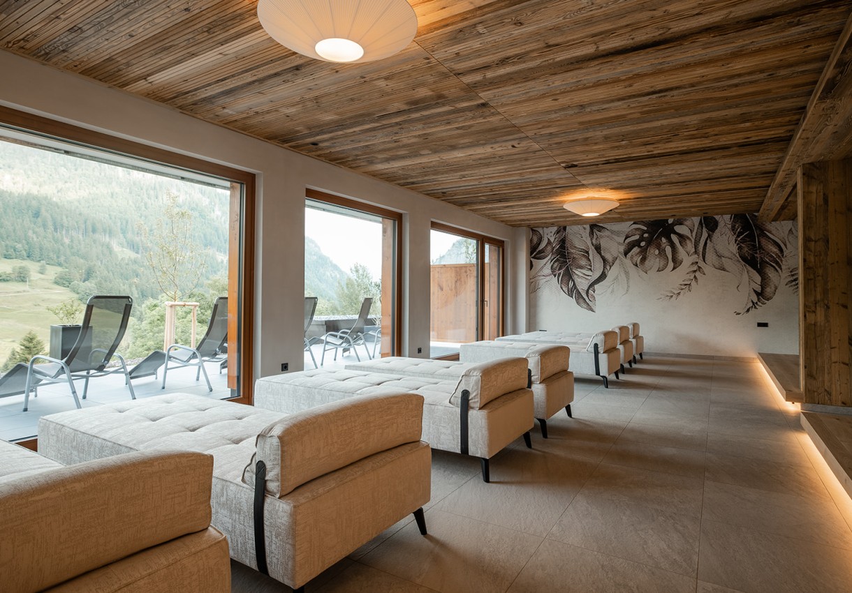 Moderner Ruheraum mit beigen Liegestühlen und großen Fenstern, die Bergblick bieten