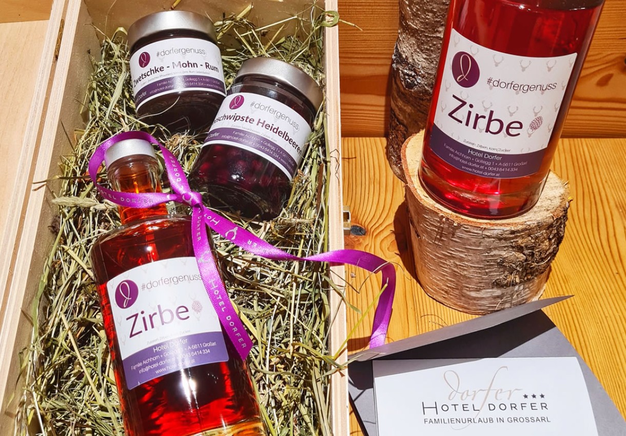 Geschenkbox mit Zirbenlikör und Konfitüren, dekoriert mit violettem Band