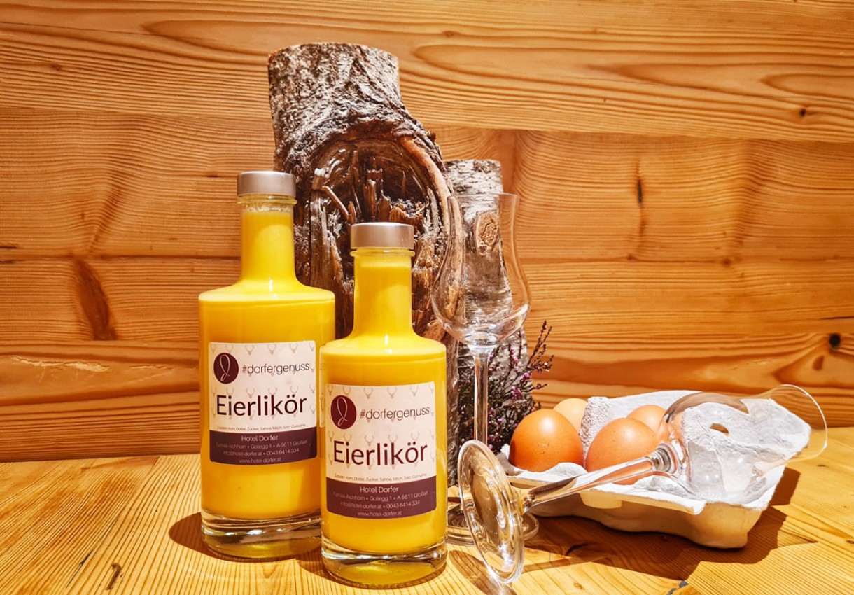 Zwei Flaschen Eierlikör mit Gläsern und Eiern auf Holztisch