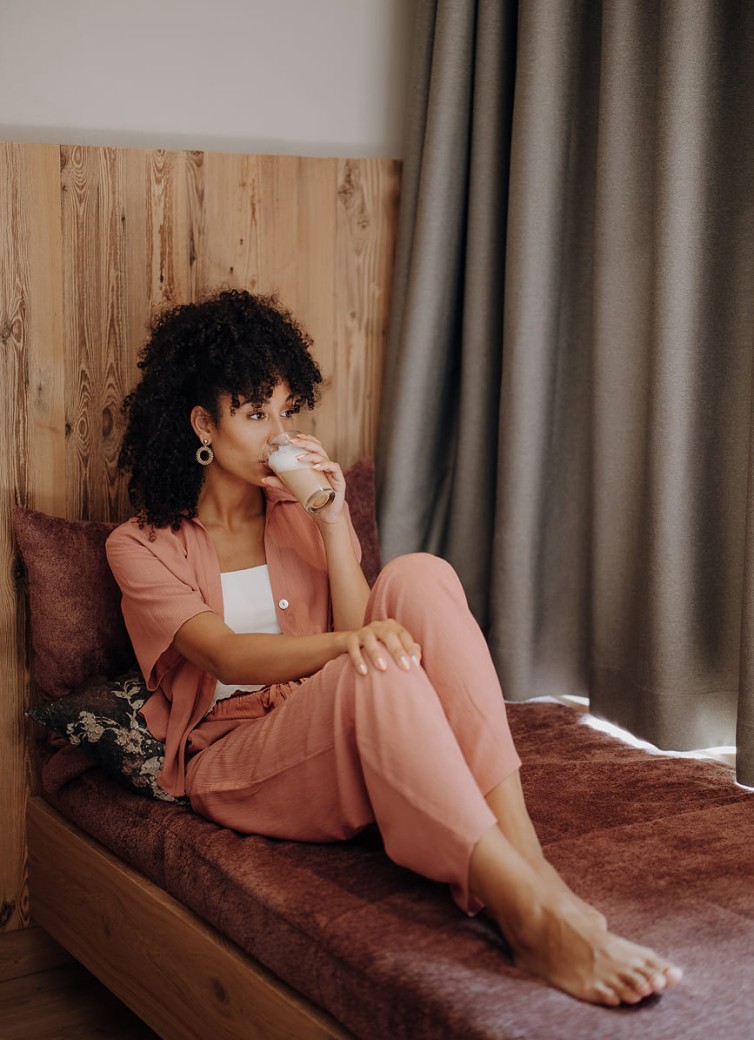 Frau entspannt auf Sitzecke im Zimmer und trinkt Kaffee