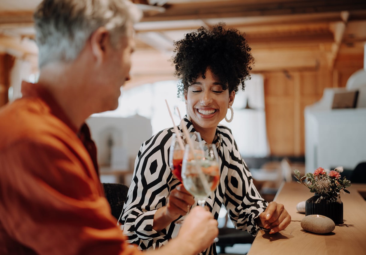 Paar stößt in der Dorfer-Hotelbar mit Drinks an und lächeln einander zu