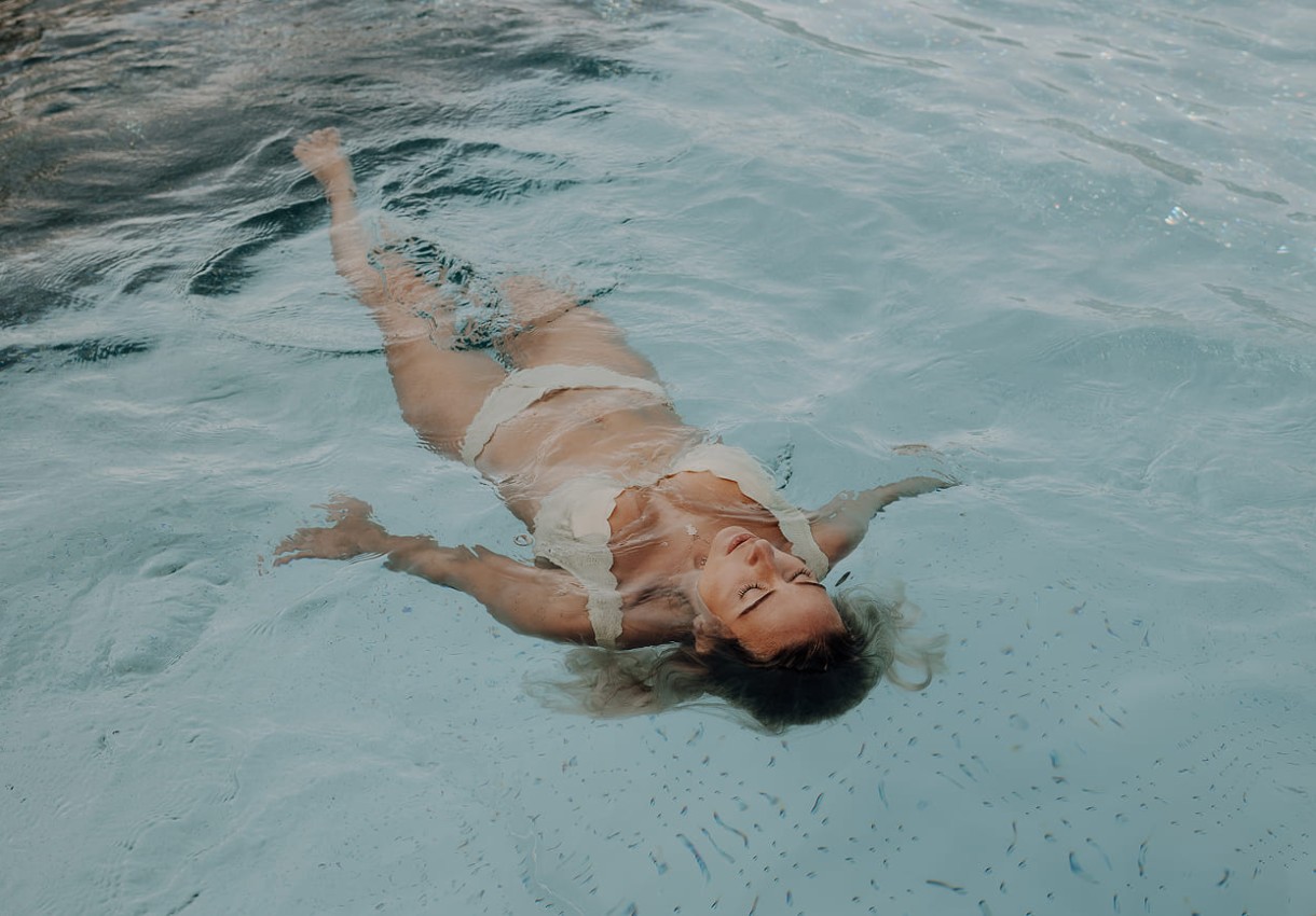 Frau treibt entspannt auf dem Rücken im Pool