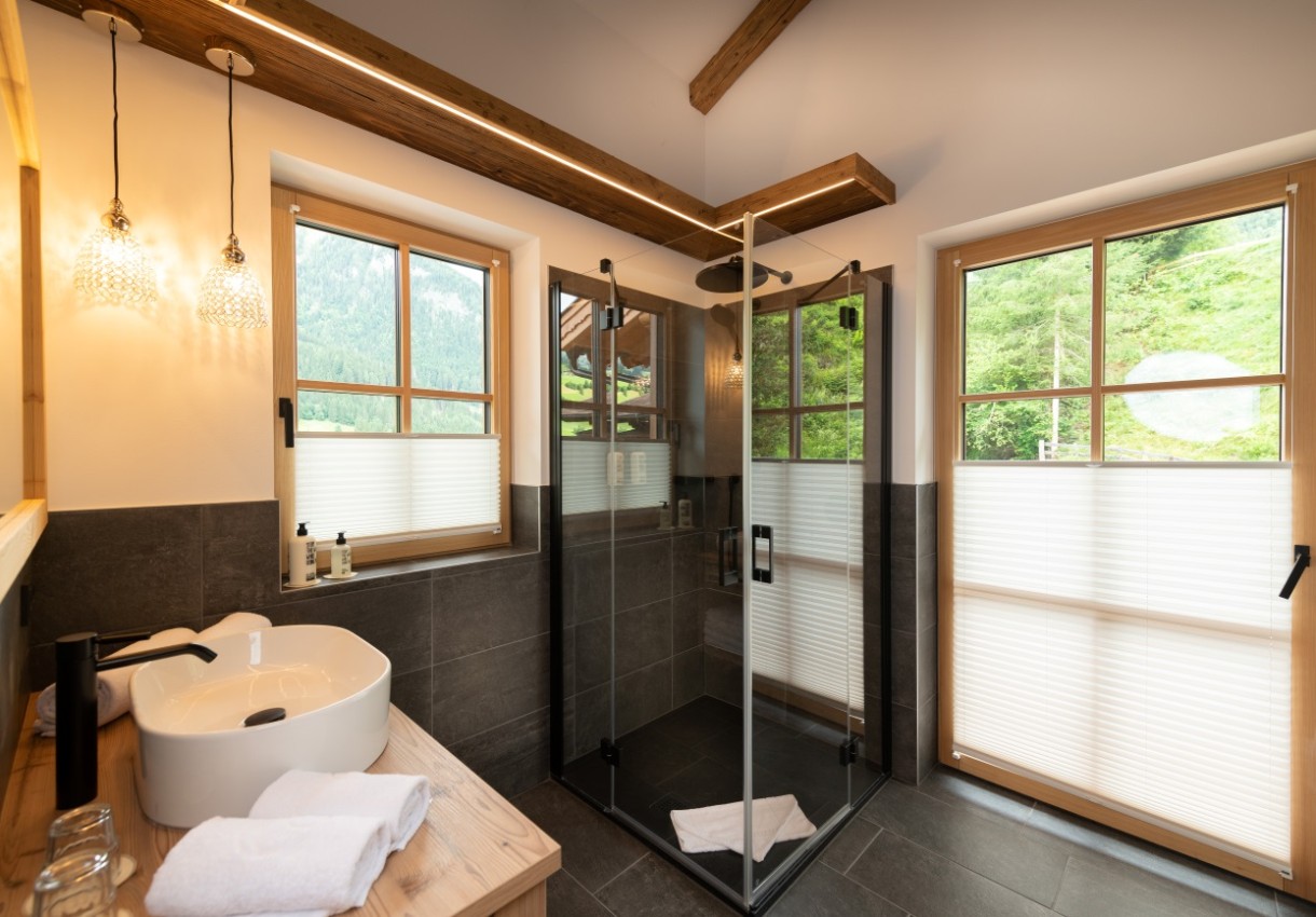 Modernes Badezimmer mit Glasdusche, Holzfenstern und Waschbecken auf Holzmöbeln