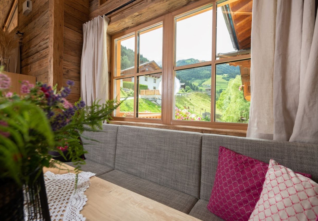 Gemütliches Wohnzimmer mit Blick auf eine grüne Berglandschaft durch ein großes Fenster