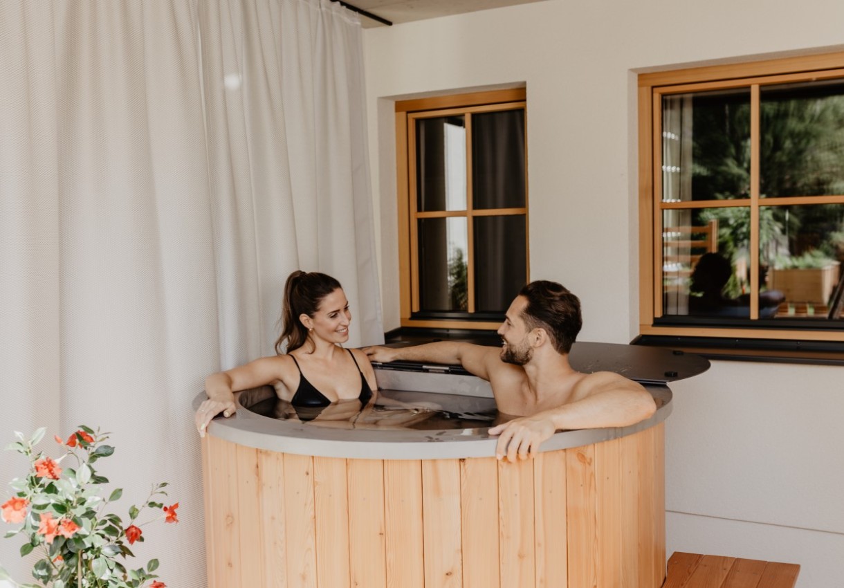 Paar entspannt sich in einem runden Holzbottich im Innenbereich