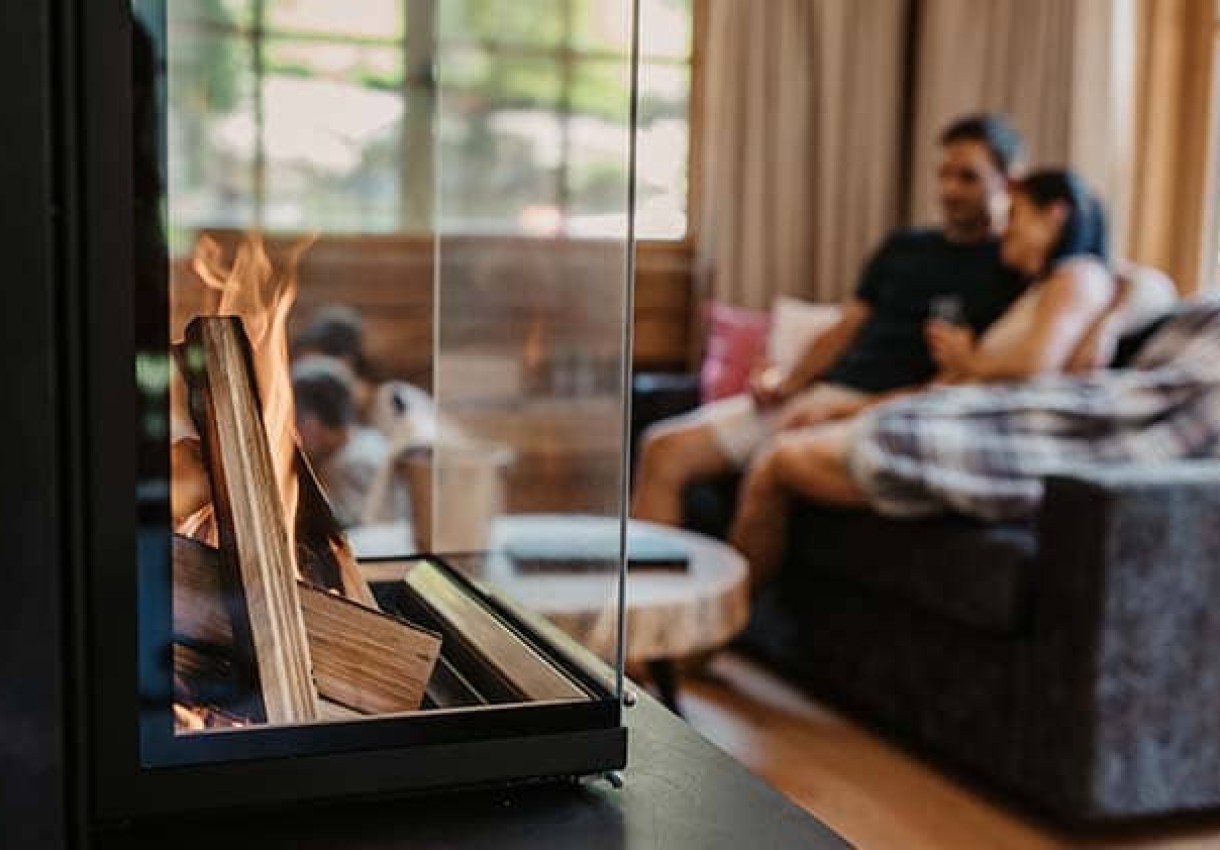 Ein Paar sitzt gemütlich auf dem Sofa vor einem Kaminfeuer