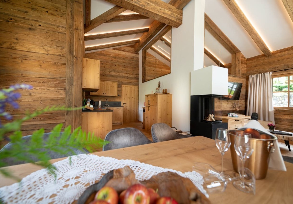 Gemütliches Wohnzimmer in einem Chalet mit Holzwänden, Kamin und moderner Küche