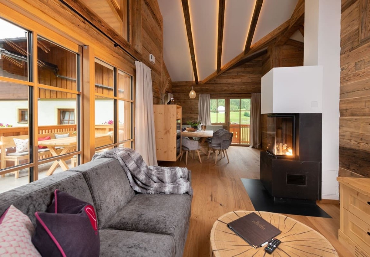 Gemütliches Wohnzimmer mit Holzverkleidung, Kamin und großer Fensterfront