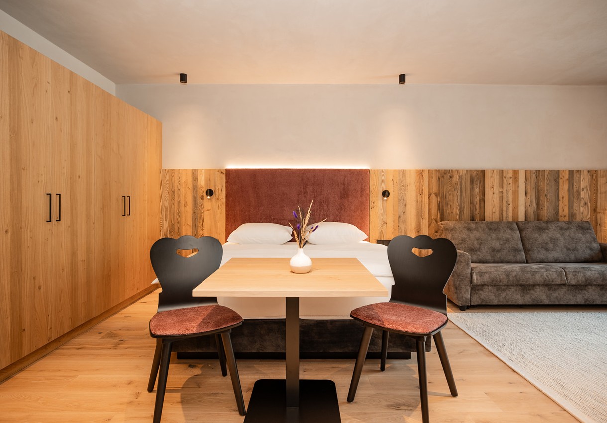 Gemütliches Schlafzimmer mit Holzmöbeln, Doppelbett und Sofa