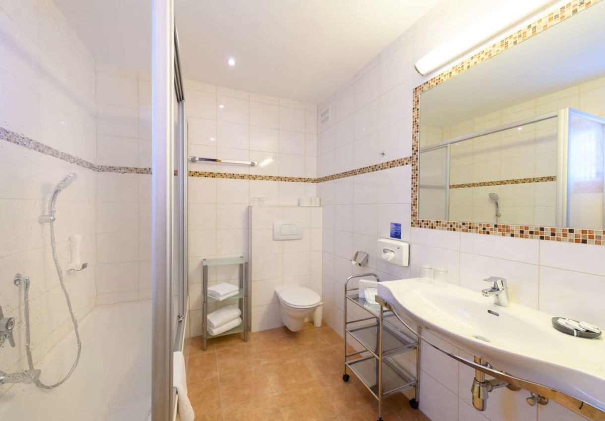 Helles Badezimmer mit Dusche, WC, großem Spiegel und Handtuchablage