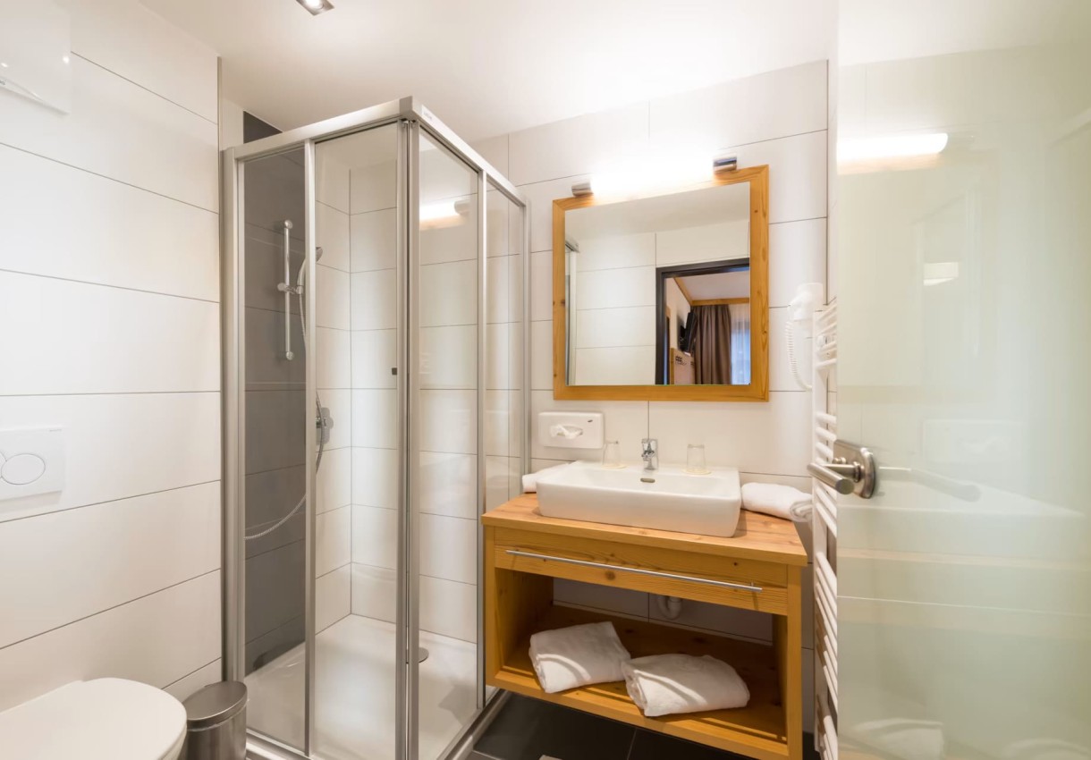 Modernes Badezimmer mit Dusche, Waschbecken und Spiegel, in hellen Tönen gestaltet