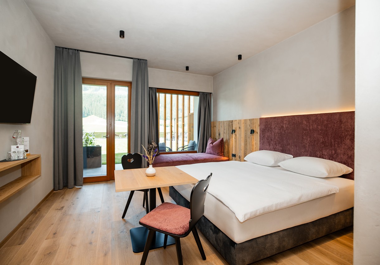 Modernes Hotelzimmer mit Doppelbett, Holzmöbeln und Balkonblick