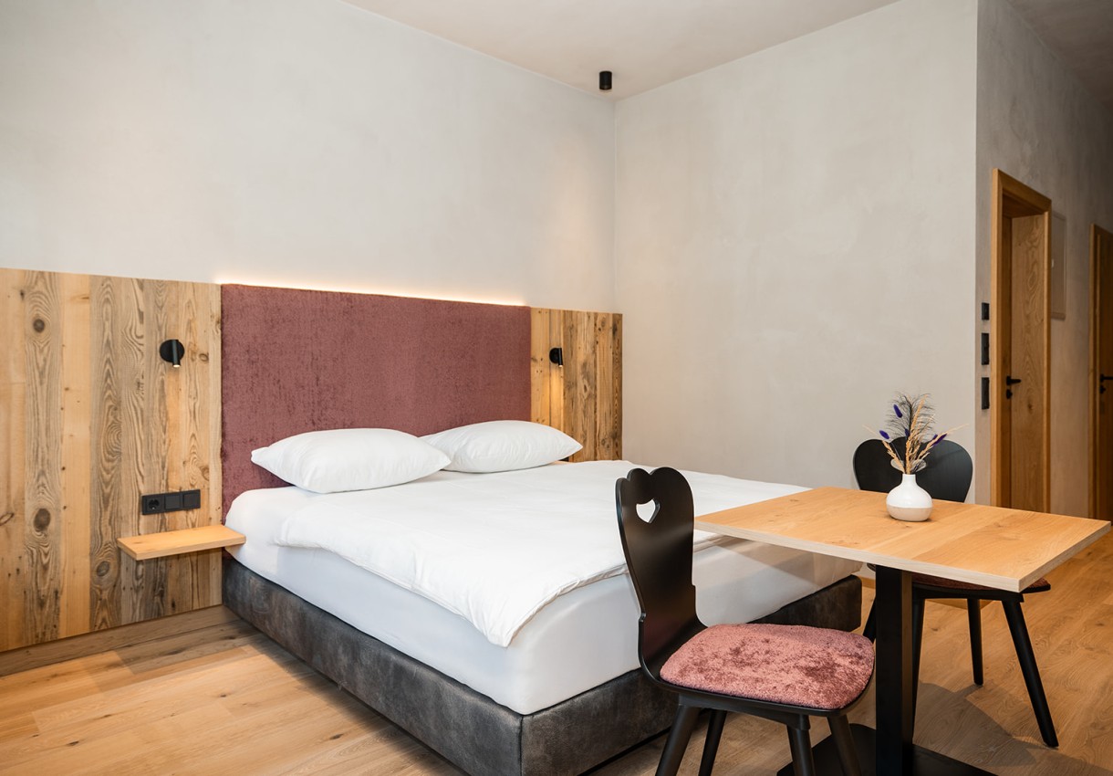 Helles Schlafzimmer mit Doppelbett, Holztisch und zwei Stühlen in modernem Design