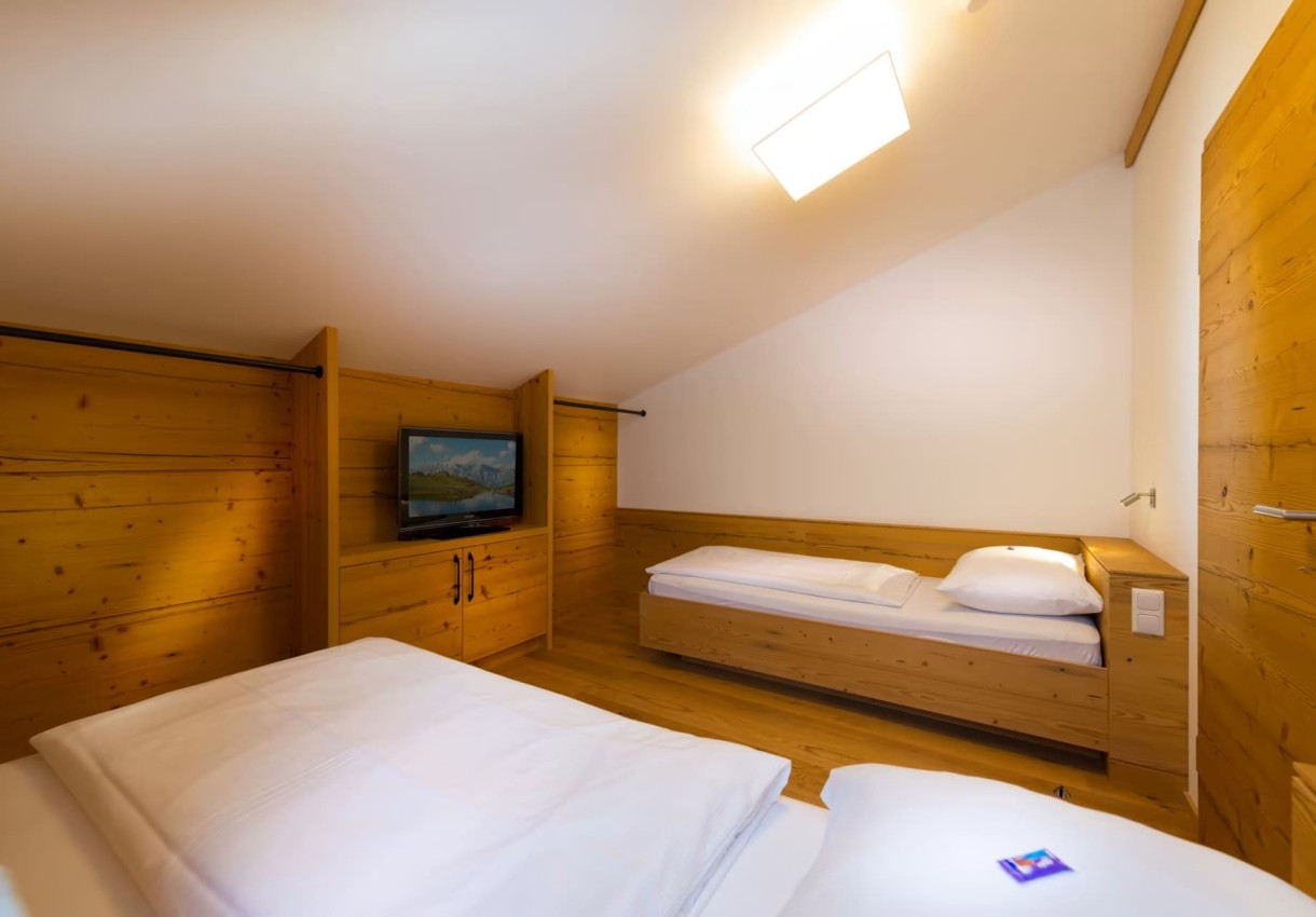 Holzvertäfeltes Schlafzimmer mit zwei Betten und einem Fernseher an der Wand