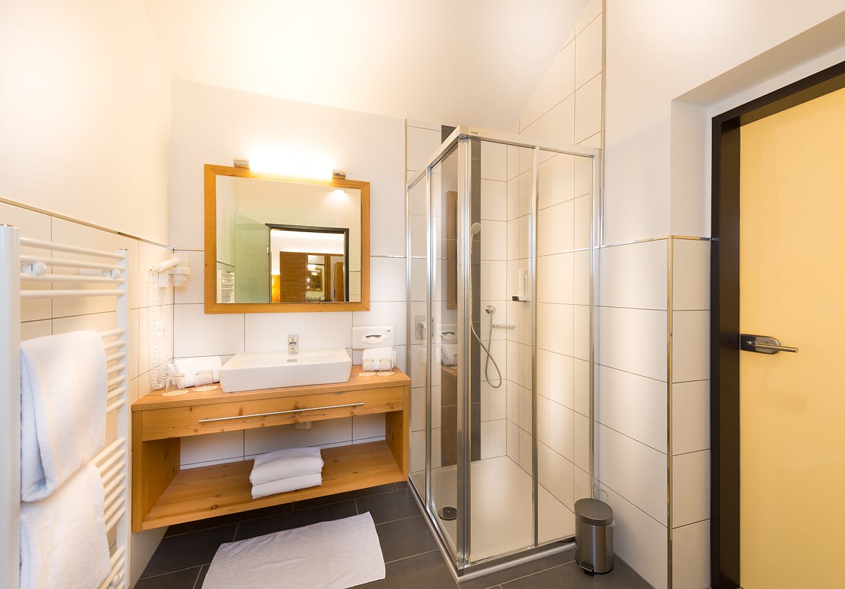 Modernes Badezimmer mit Dusche, Waschbecken, Spiegel und Handtuchhalter