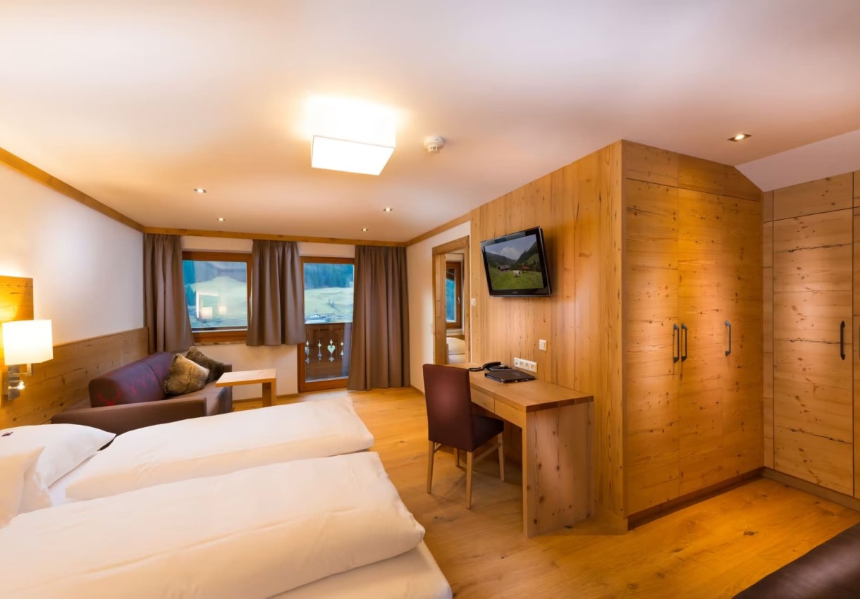 Ein gemütliches Hotelzimmer mit Holzverkleidung, Doppelbett und Balkonblick